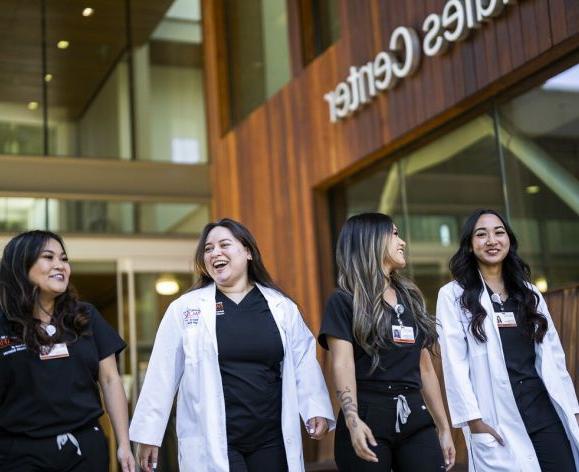 照片显示，正规博彩十大网站健康科学学院的四名护理专业学生微笑着走近护理教室.